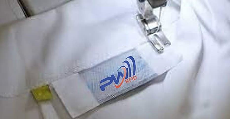 Etiqueta PW RFID sendo costurada em uma peça branca, sob o pé da máquina de costura