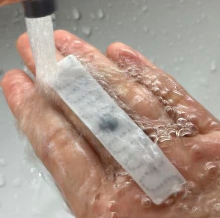 Etiqueta RFID sendo lavada sob água corrente na palma da mão