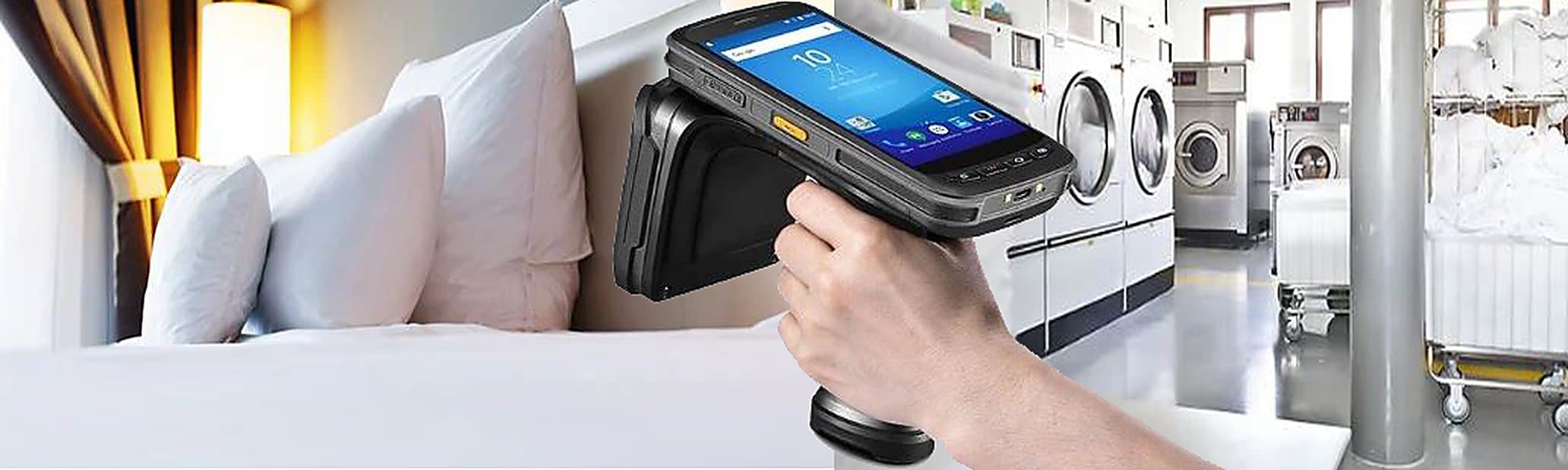 Cama de hotel arrumada, leitor RFID de mão em uso e lavanderia industrial com carrinhos de enxoval